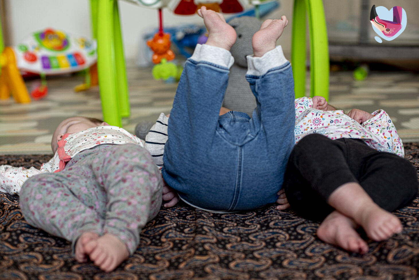 Troje niemowląt leżących obok siebie w Tuli Luli.
