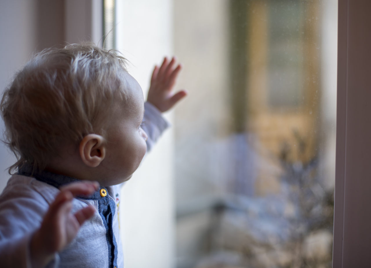 Małe dziecko patrzące przez okno.