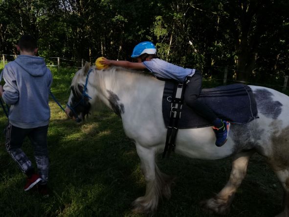 Dziewczynka jadąca na koniu prowadzonym przez instruktora