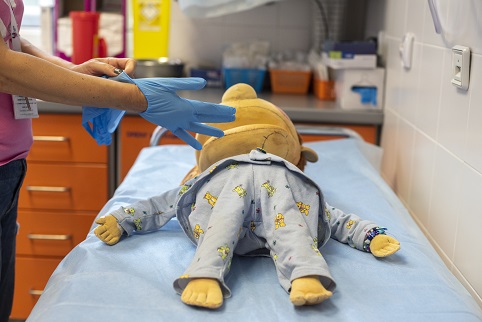 onkologia lalka Edek lezaca na lezance w pokoju zabiegowym rece zakladajace rekawiczki o zabiegach przeszczepiana szpiku poradnik onkologiczny