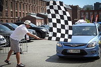 rozpoczęcie wyścigu mężczyzna macha flagą w czarno białą kratkę przed maską samochodu