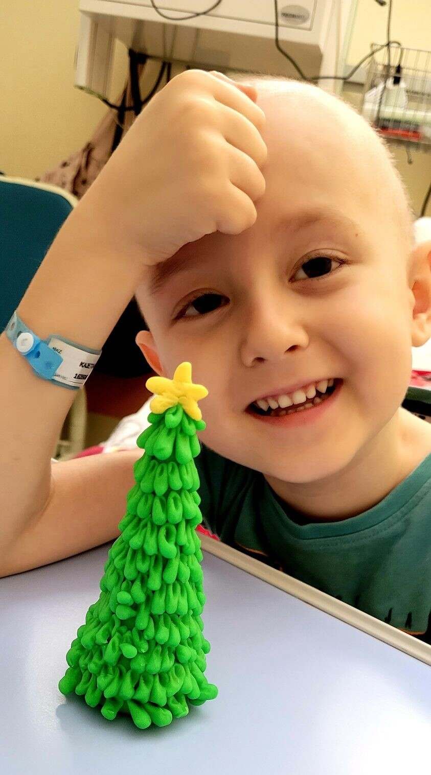 Chłopiec po chemioterapii bawi się figurką choinki