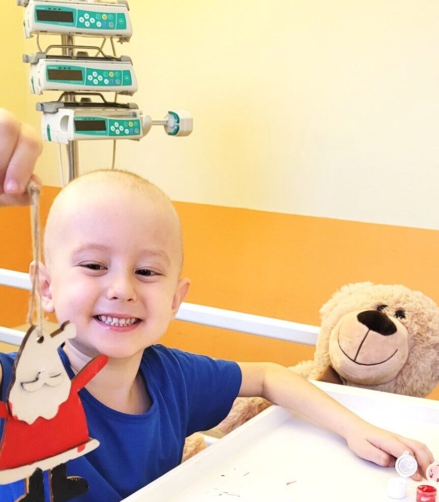 Chłopiec po chemioterapii bawi się figurką Mikołaja