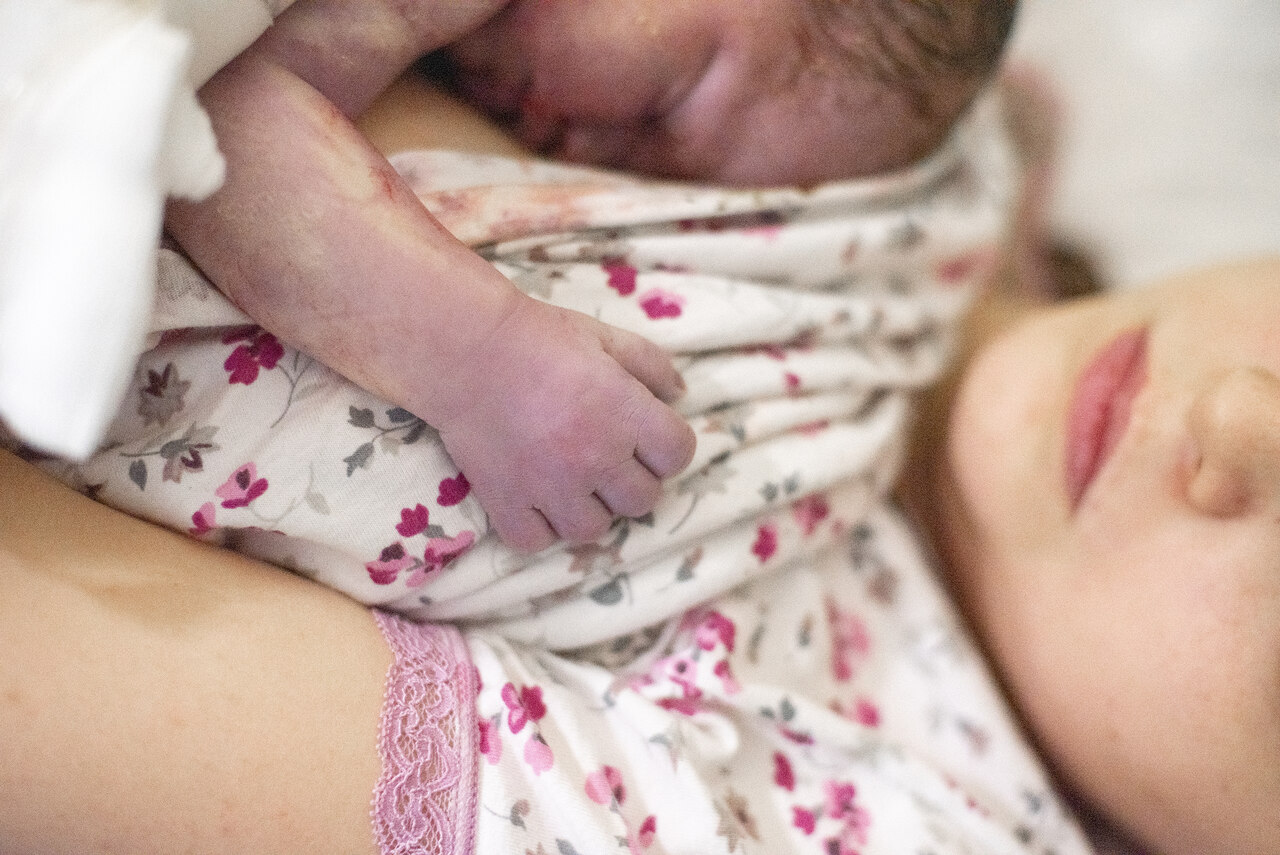 Noworodek po porodzie przytulony do piersi mamy