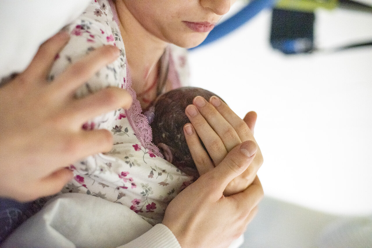 Mama podtrzymuje główkę swojego dziecka zaraz po porodzie