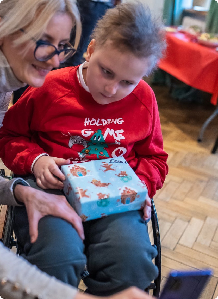 Pomoc w chorobie onkologicznej Mama Dawida z Dawidem rozpakowują prezenty Program OKNO raport 2024